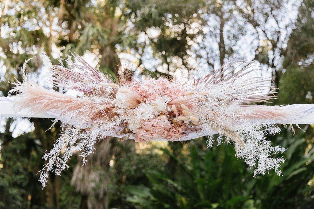 Dried wedding arbour flowers in shades of soft pink on a wedding arch