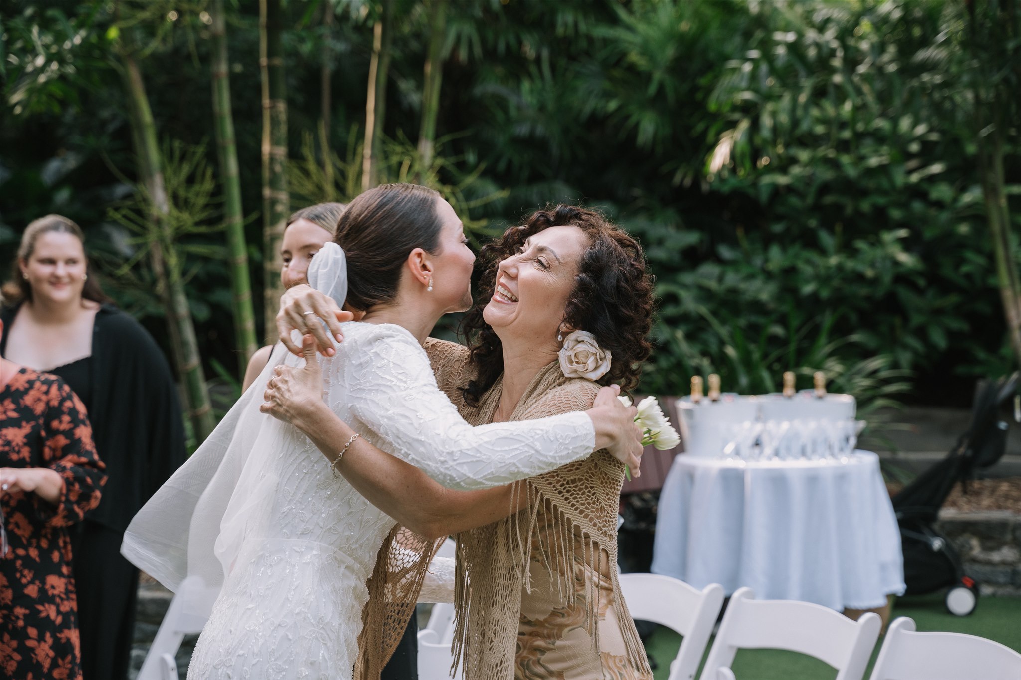 guest congratulates bride a well dressed lady hugging the bride with the drinks table in the backdrop of the garden wedding